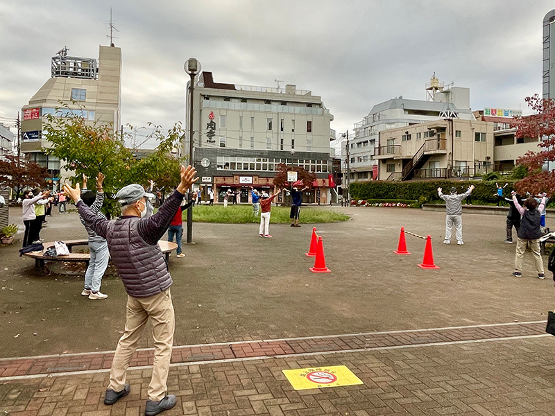 駅前でラジオ体操する人々の写真